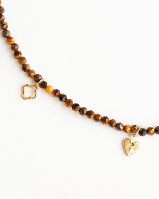 Natural Tiger Eye beaded charm necklace with five 18K gold charms, including hand, flower and heart motifs.
