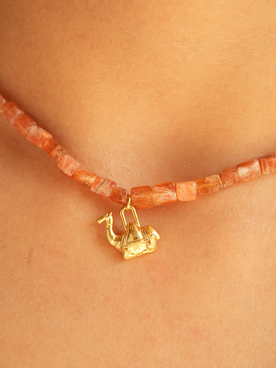 Macro close-up of the gold camel charm with clover accents on PEHRO's natural sunstone beaded choker in 925 silver