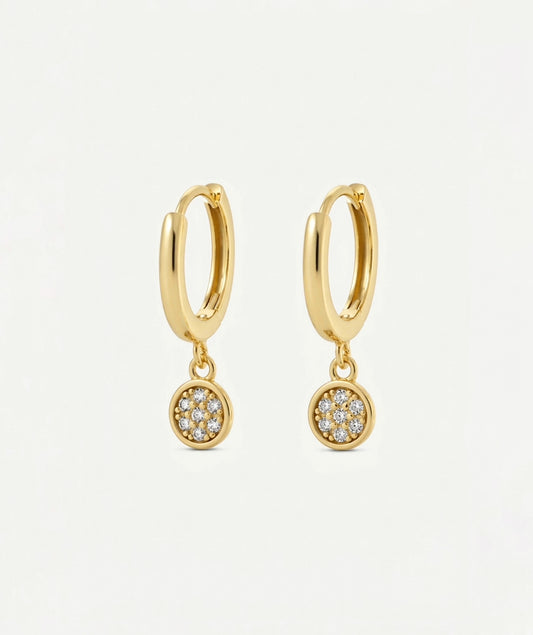 A pair of gold huggie hoop earrings with small circular pavé dangle charms set with clear stones, shown on a clean white background.