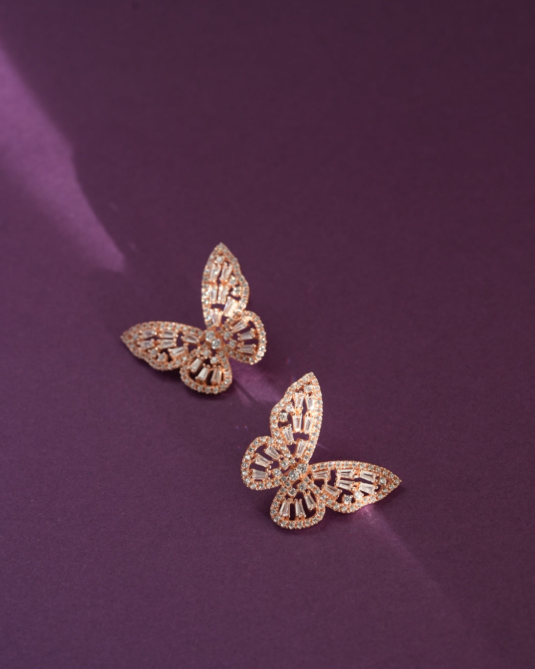 A luxurious pairing of the 925 Sterling Silver Aurora Butterfly Stud Earrings resting on a deep, premium background, highlighting the radiant stones and sculptural design.