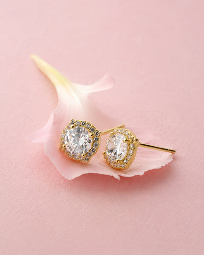 Pair of gold-toned stud earrings with large center clear stones and a sparkling halo border on a pink petal.