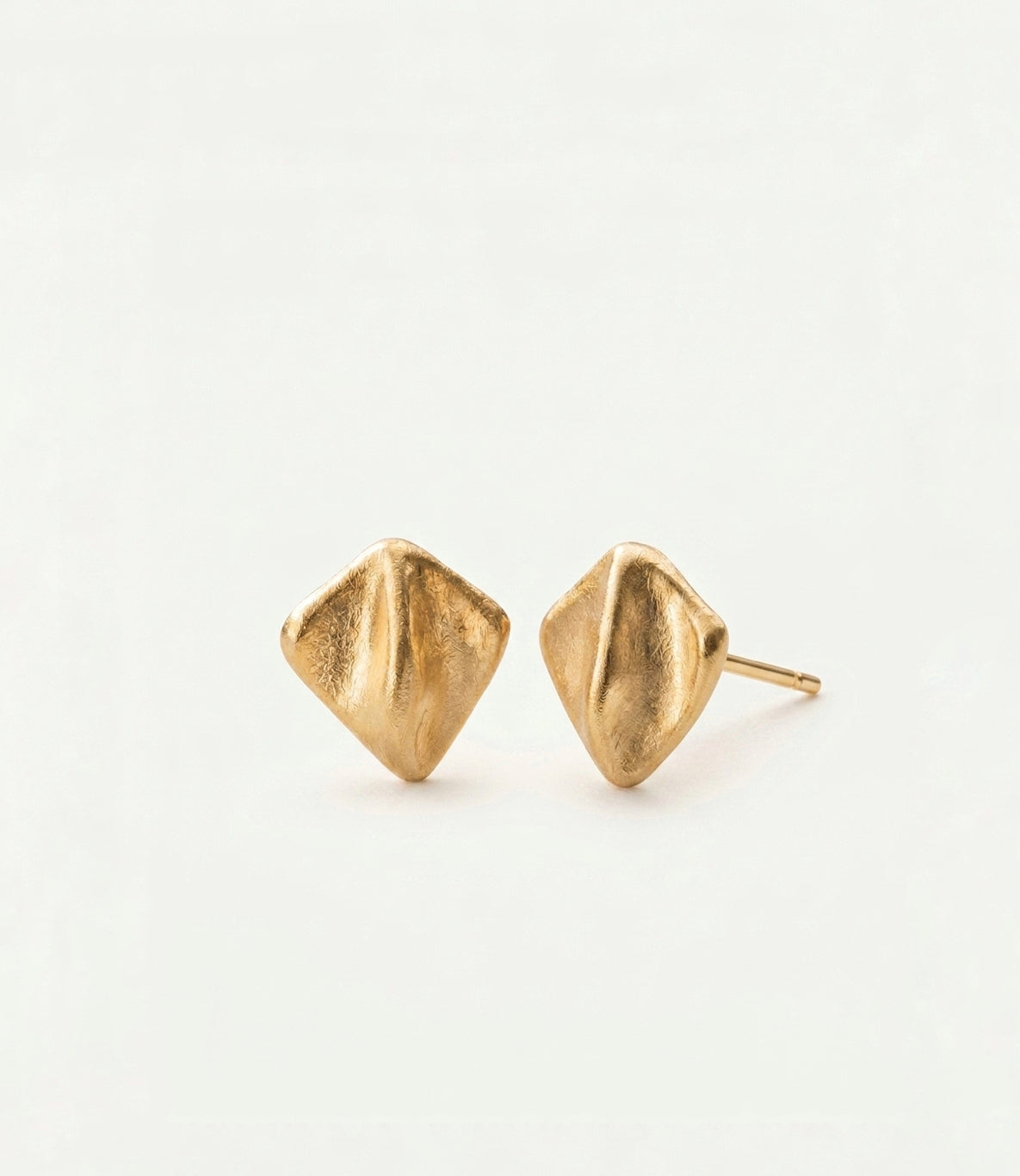 A pair of gold geometric stud earrings with a textured, organic diamond-like shape, displayed on a clean white background.