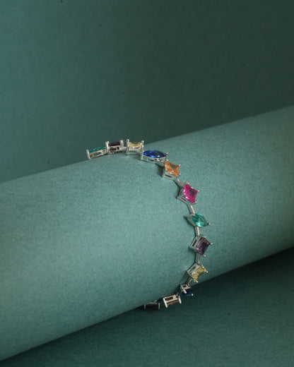 The 925 Sterling Silver Multicolor Station Bracelet draped over a minimal sculptural form, highlighting its lightweight construction and rhodium finish.