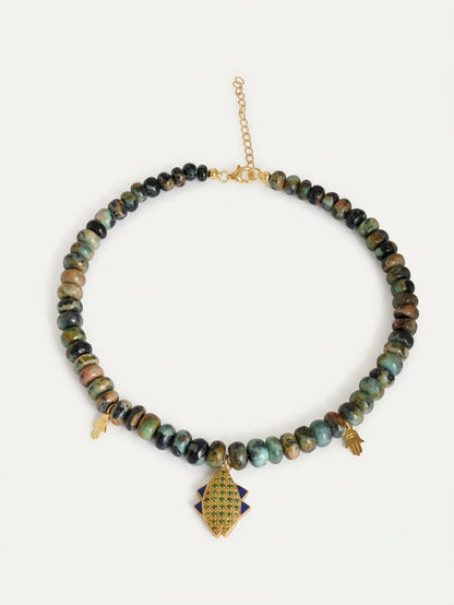 op-down view of the PEHRO 925 Sterling Silver Chrysocolla Beaded Choker featuring 18K gold vermeil fish and hamsa charms on a pure white background.