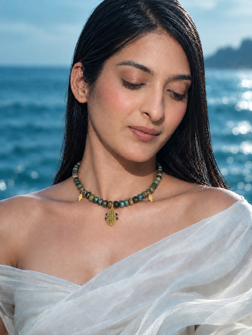 A woman elegantly styling the PEHRO gold vermeil chrysocolla beaded choker over a white silk drape, highlighting how the natural stones rest beautifully on the collarbone.