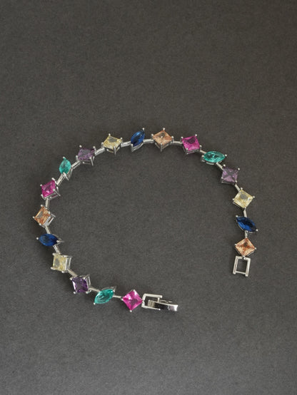The 925 Sterling Silver Multicolor Station Bracelet draped over a minimal sculptural form, highlighting its lightweight construction and rhodium finish. On a dark gray background 