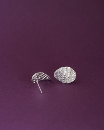 Pair of silver-tone teardrop-shaped stud earrings with baguette-cut clear stones on a dark purple background