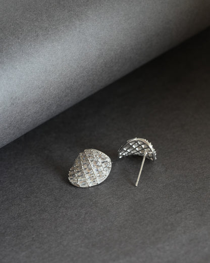 Pair of silver-tone teardrop-shaped stud earrings with baguette-cut clear stones on a dark gray background