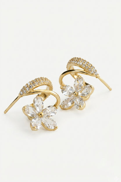 A pair of gold-toned drop earrings featuring a curved bar set with small clear crystals and a dangling flower-shaped crystal cluster at the bottom, shown on a plain white background.
