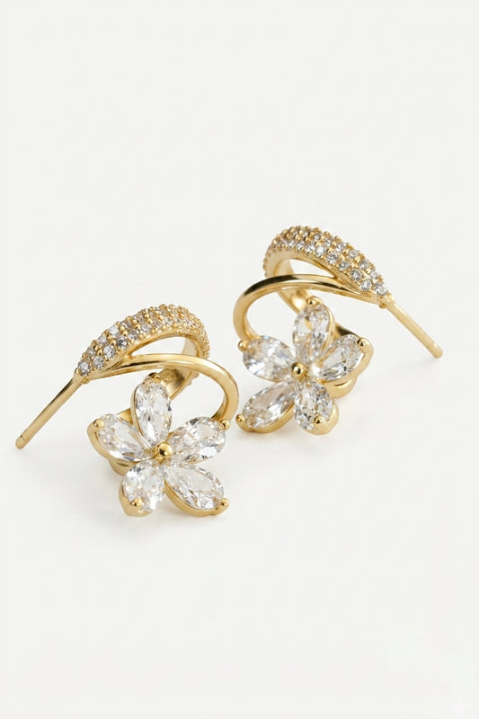 A pair of gold-toned drop earrings featuring a curved bar set with small clear crystals and a dangling flower-shaped crystal cluster at the bottom, shown on a plain white background.