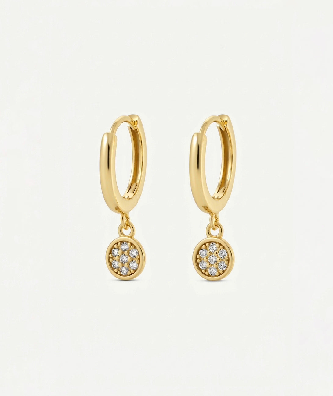 A pair of gold huggie hoop earrings with small circular pavé dangle charms set with clear stones, shown on a clean white background.