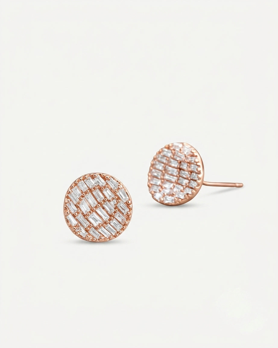 A pair of round rose gold stud earrings with a textured grid pattern of clear baguette and round-cut stones, shown on a clean off-white background.